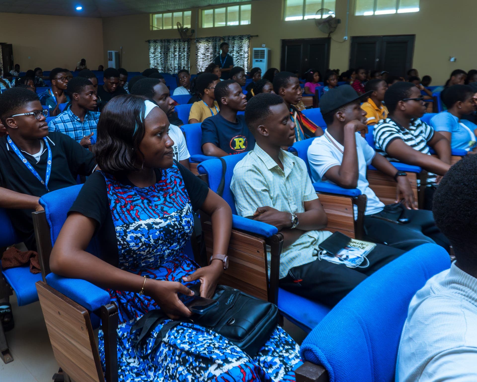 Attendees in blue auditorium seats listening to a session